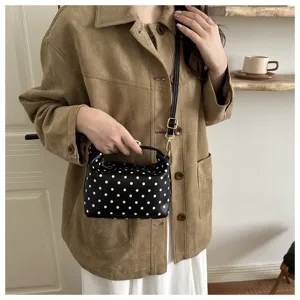 Detail shot of black and white polka dot cosmetic bag with handle and strap in cozy room.