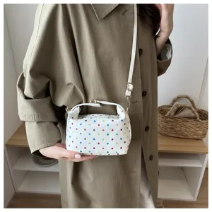 Detailed shot of white colorful polka dot cosmetic bag held by model, versatile daily pouch.
