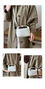 Detailed view of white colorful polka dot cosmetic bag with shoulder strap and metal hardware.