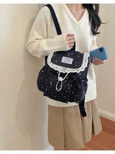 Vue détaillée d'un sac à dos noir avec imprimé étoiles, bordure en dentelle et cordon.