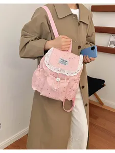 Vue détaillée d'un sac à dos rose à imprimé étoiles avec une fine bordure en dentelle blanche.