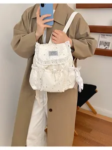 Joli mini sac à dos blanc avec imprimé étoiles, bordure en dentelle et poche avant pratique.