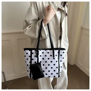 Vista di dettaglio di una chic borsa tote a pois bianchi e neri con pochette coordinata.