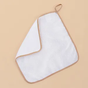 Close-up detail of white microfiber cleaning cloth with neat brown edge binding and hanging loop.