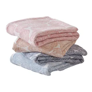 Stack of three soft cotton gauze summer blankets in pink orange and blue with rose patterns.