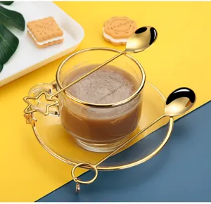Creative gold rim glass cup and saucer set with stylish star and ring shaped stirring spoons.