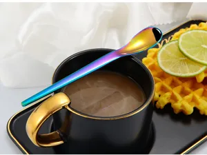 Close-up of a vibrant rainbow stainless steel spoon resting on a stylish black and gold coffee cup.
