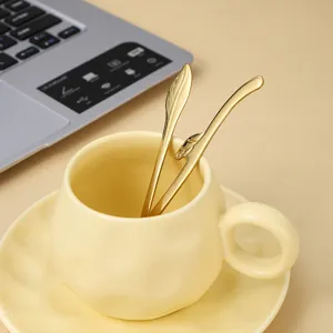 Elegant ceramic coffee cup and saucer set with luxury gold leaf-shaped spoons for home.