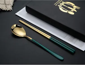 Dettaglio posate in acciaio inossidabile con finitura oro lucido e manico verde elegante.