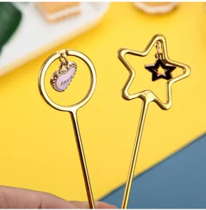 Details of creative gold stainless steel stirring spoon with cute heart and star charms inside.