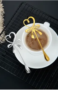 Cuillère à café élégante en acier inoxydable avec motif de cœur et nœud, or et argent.
