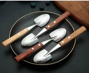Close-up detail of stainless steel shovel spoons with wooden handles displayed on a plate.