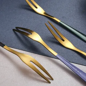 Set di forchette da frutta in acciaio inox con rebbi dorati e manici colorati.