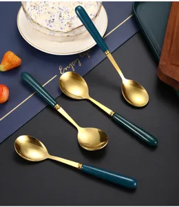 Detailed view of ceramic handle stainless steel spoon with gold finish for dining soup use.