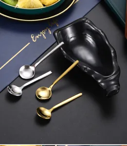 Detailansicht von kleinen Edelstahllöffeln im Set mit Keramikschale in Gold und Silber Ausführung.