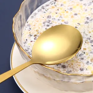 Golden stainless steel soup spoon with elegant glass bowl and saucer set for daily table decor.
