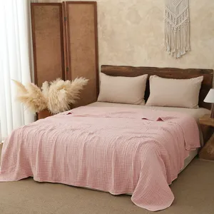 Detailed view of the soft pink six-layer cotton gauze summer quilt in a cozy bedroom.