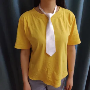 Dettaglio in primo piano di una cravatta corta bianca in satin su maglia gialla, tessuto.