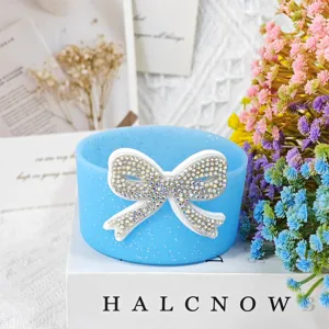 Detail shot of blue silicone cup sleeve with sparkly rhinestone bow for bottle protection.