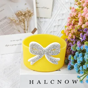 Yellow silicone cup sleeve with rhinestone bow detail, Stanley cup accessory close up.