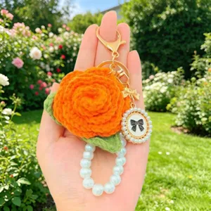 Handgestrickter orangefarbener Rosen-Schluesselanhänger mit Perlenband und eleganter Taschendetail.