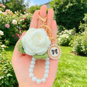 Handgefertigter weißer Häkelrosen-Schlüsselanhänger mit Perlentaschenkette und Vintage-Schleifen-Charm.