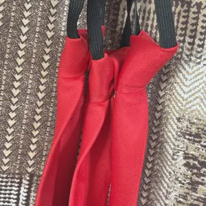 Vista detallada de una corbata pequeña roja lisa prehecha con correa elástica negra para estudiantes.