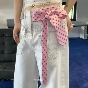 Raspberry pink polka dot tie paired with white embroidered vintage jeans for women.