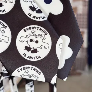 Close-up detail of children black and white printed necktie with quirky funny graphic text.