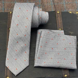 Detail view of mens gray fine checked tie and pocket square set with red star pattern.