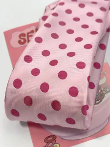 Close-up detail of raspberry pink polka dot tie, showcasing textured fabric and magenta dots.