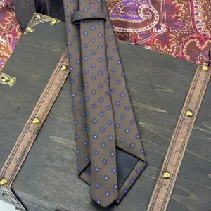 Brown men necktie detail featuring blue floral jacquard pattern, elegant business suit accessory.