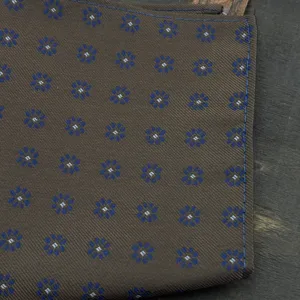 Close-up detail of mens brown pocket square featuring elegant blue floral jacquard pattern.