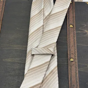 Vista detallada de la corbata de rayas jacquard de lujo en elegante tono beige champán.