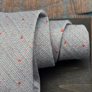 Men's fine grid grey tie with red star speckles, elegant formal neckwear detail for suit.
