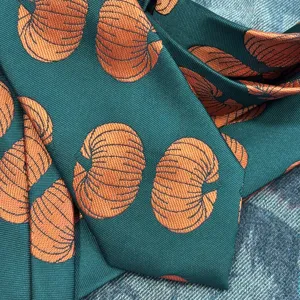 Dark green woven necktie featuring unique orange pumpkin pattern, vintage style fashion detail close-up.