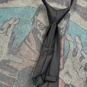 Detailed view of the black zipper necktie, featuring a convenient pull-up design and textured fabric.