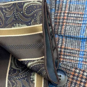 Detail shot showing high-density jacquard paisley and striped tie fabric texture and neat edge stitching.