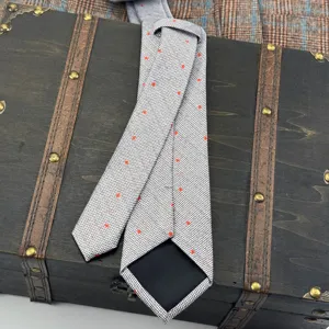 Grey fine grid necktie with red star dot print, elegant men's formal business accessory detail.