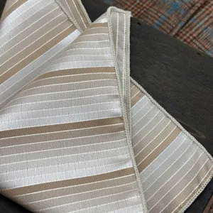 Vista detallada de tela para corbata de jacquard a rayas, tono beige champán.