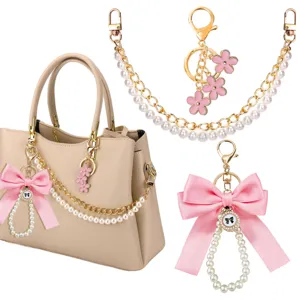 Beige handtas con parelketting en roze strik sleutelhanger set voor elegante stijl.