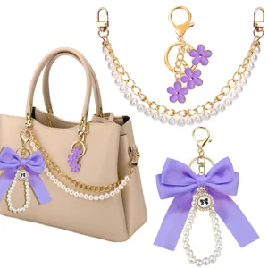 Set van parelketting en paarse strik tassenhanger, elegante handtas accessoires en sleutelhangers.