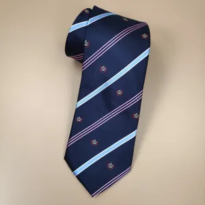 Detail shot of navy blue student uniform tie with pink and light blue stripes and crown embroidery.