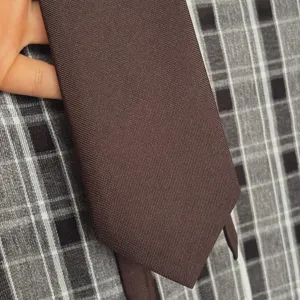 Corbata lisa marron vista de detalle, textura de tela fina para atuendos diarios.