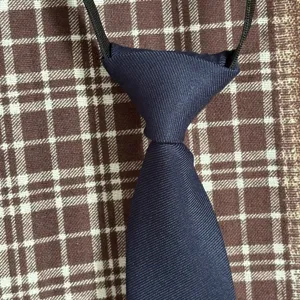 Corbata prehecha azul marino para niños, detalle de tela de poliéster mate con elástico.