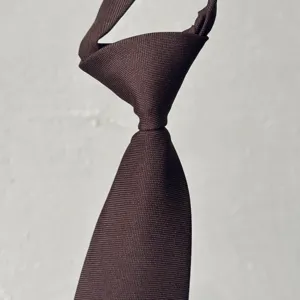 Primer plano detallado de una corbata marrón lisa en un elegante estilo retro.