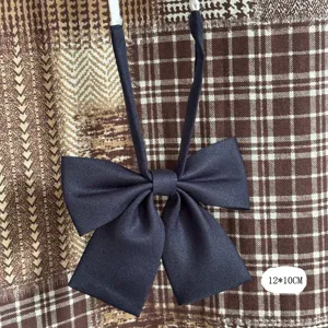 Detalle de pajarita de poliéster mate azul marino para camisas de uniforme escolar.