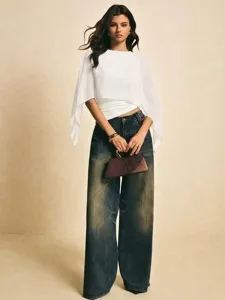 Vista detallada de la elegante blusa de gasa con mangas de capa y vaqueros anchos.
