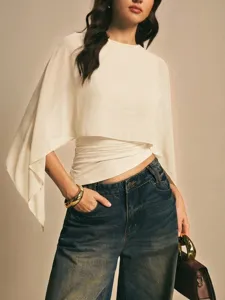 Detalle de la elegante blusa de gasa con mangas capa irregulares y vaqueros modernos.