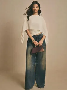 Detalle elegante blusa blanca de gasa con mangas capa, top asimétrico holgado de moda.